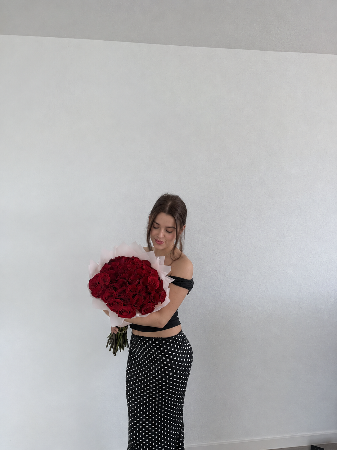Maya holding a bouquet of red roses